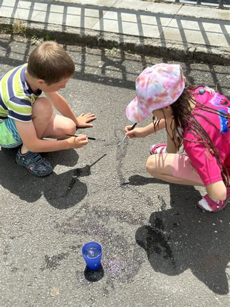 Deti maľujú vodou a štetcom na chodník.