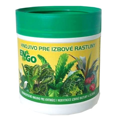 dve ruky držia vedierko s bielymi granulami hnojiva, v pozadí zelené rastliny