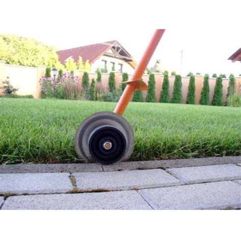 Detailný záber na strunovú kosačku pri úprave okrajov trávnika pozdĺž záhradného chodníka