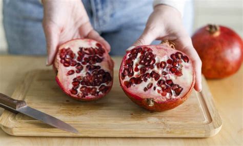 fotografia zrelého granátového jablka s rozpolenou kôrou ukazujúcou arily