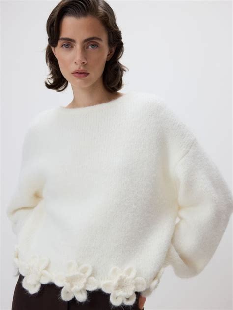 Detail plastového domčeka s imitáciou tehlového obloženia a kvetinovou výzdobou.