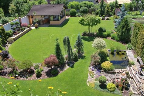 Záhon kvitnúcich rastlín pred tujami