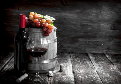 Drevený sud s hroznom, fľašou vína a pohárom v rustikálnom prostredí