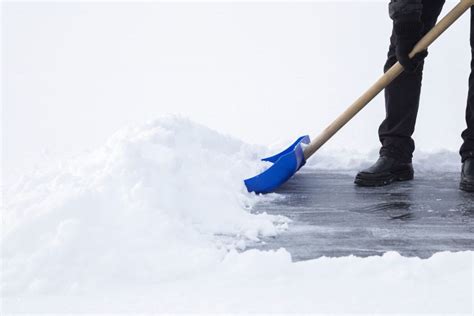 Ilustračná fotografia znázorňujúca upratovanie snehu na chodníku pred bytovým domom.