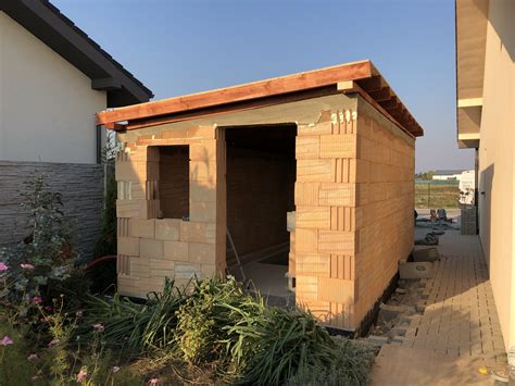 Záber na udržiavaný murovaný záhradný domček v obklopení zelene a ovocných stromov