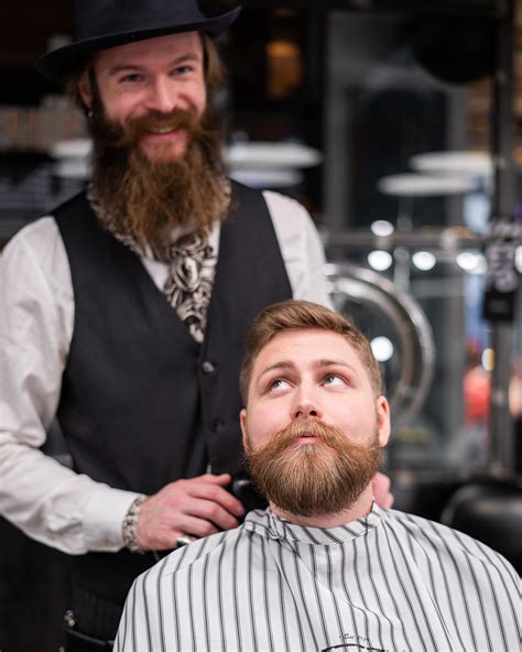 Fotografia barbera upravujúceho bradu zákazníkovi