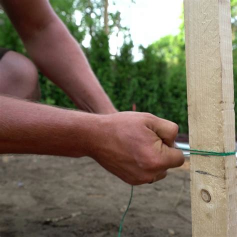 Detailné zobrazenie upevnenia siete k drevenému kolu pomocou pások