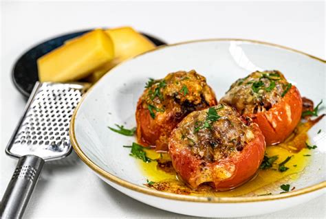 Ilustračná fotografia pripravených surovín na plnené rajčiny: čerstvé rajčiny, miska so syrovou penou, nasekané bylinky