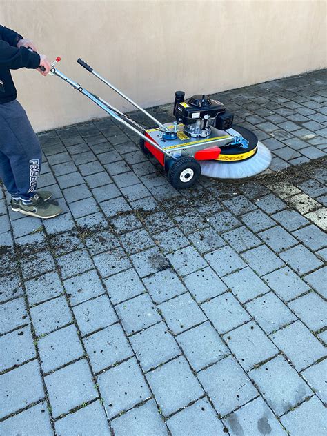 Odborník používajúci vysokotlakový čistič na odstránenie buriny z dlažby