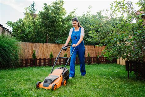 Ilustračná fotografia ženy kosí trávnik akumulátorovou kosačkou bez pojazdu.